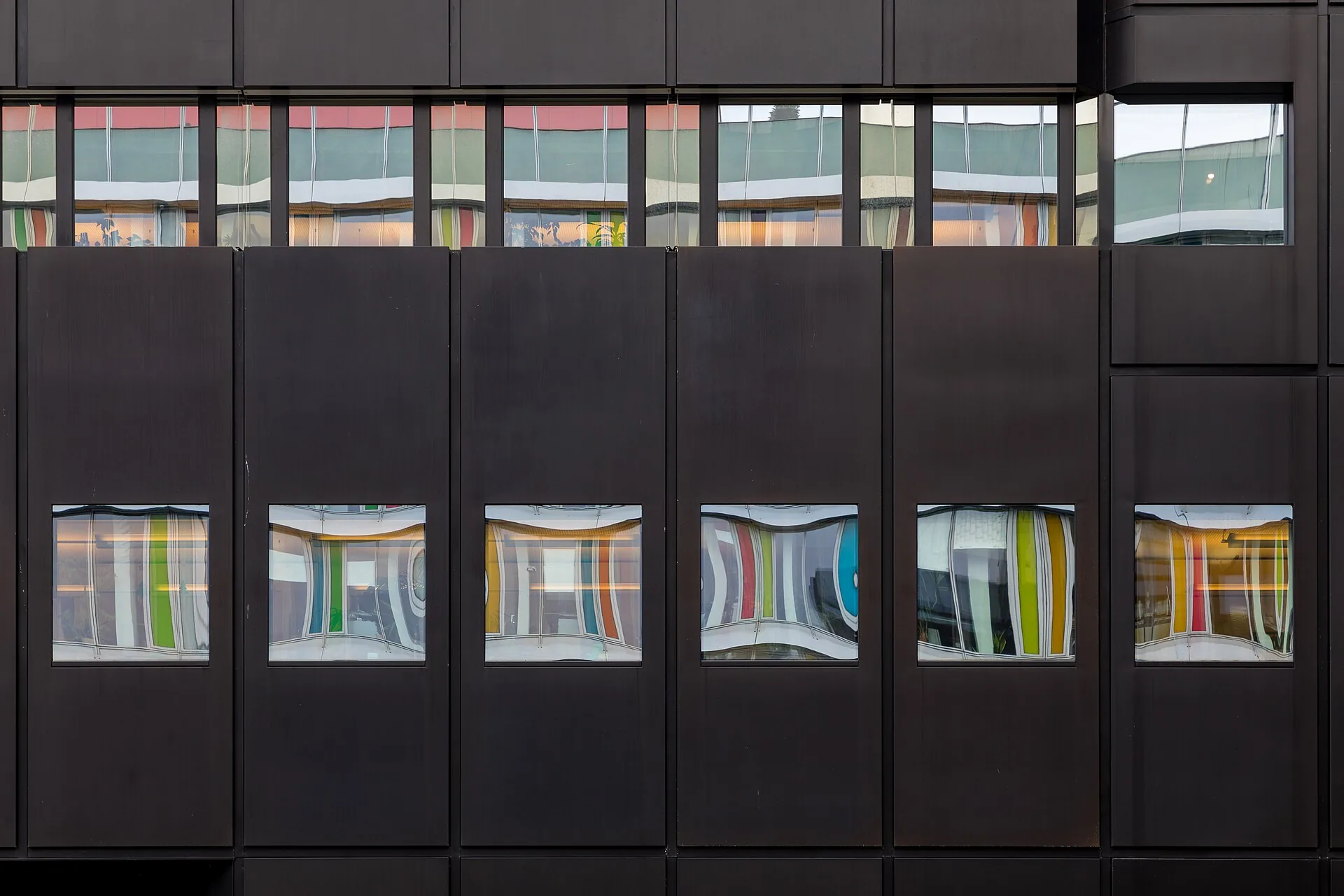 Dark building facade with a row of reflective windows