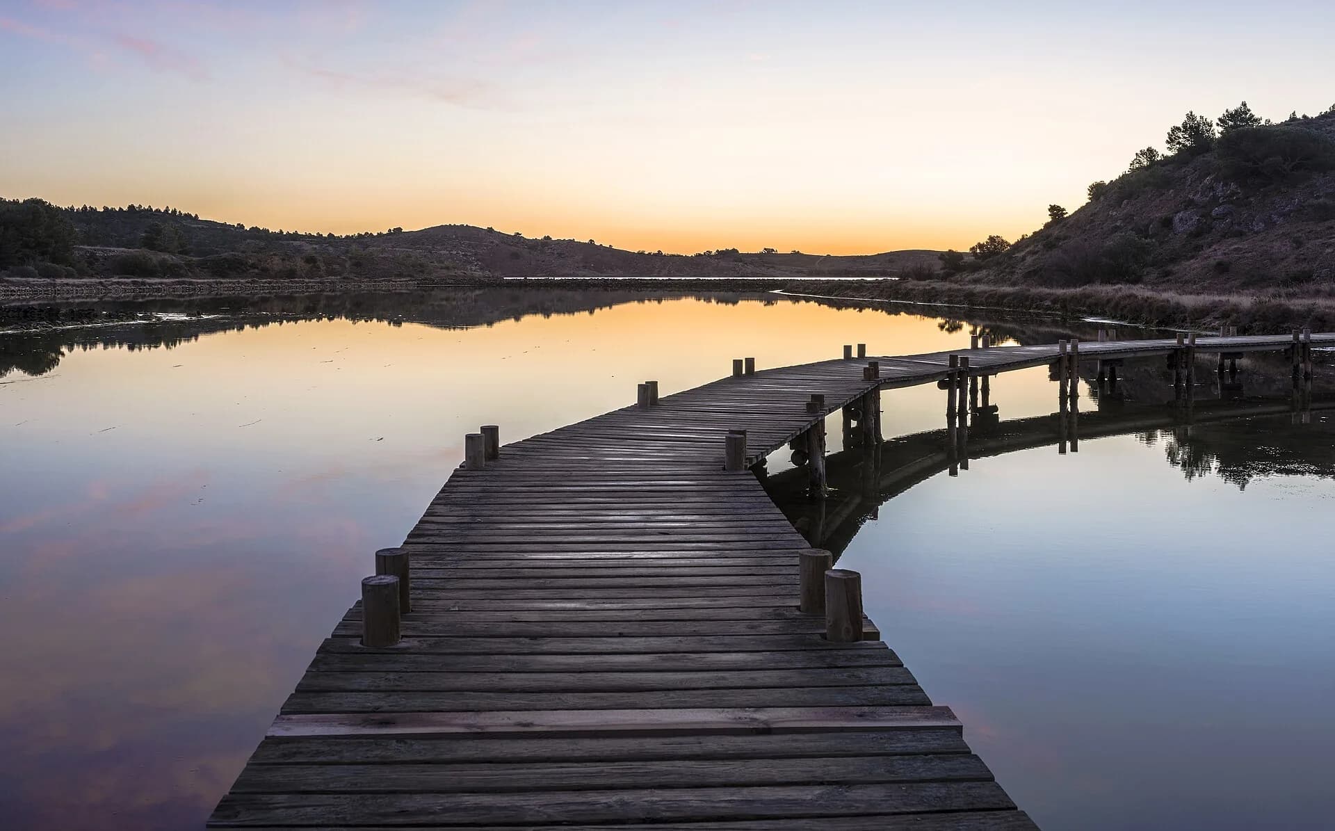 Wooden jetty reaching into a still lagoon at dusk